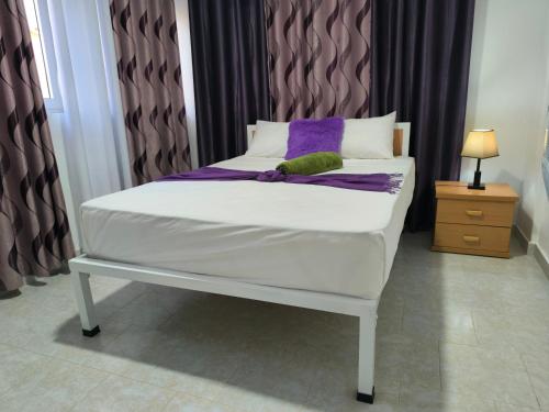 a white bed with purple and green pillows on it at Plateau Bedroom & Chambre - Praia Center 1 in Praia