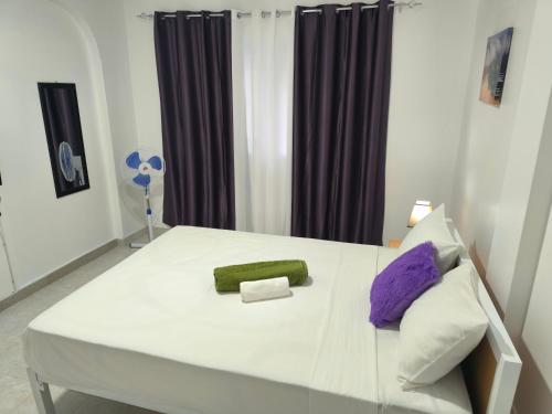 a white bed with a green and purple pillow at Plateau Bedroom & Chambre - Praia Center 1 in Praia
