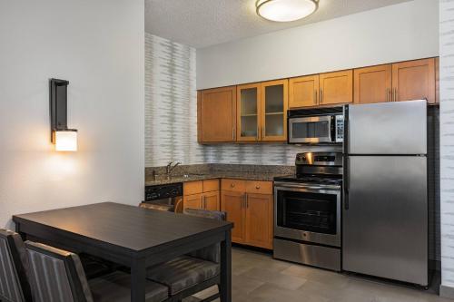 a kitchen with a table and a stainless steel refrigerator at Residence Inn Louisville Downtown in Louisville