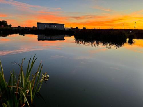 a building on the water with a sunset in the background at The Kings Head inn in Addlethorpe