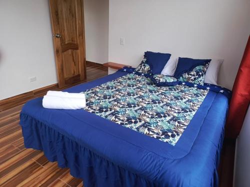 a bed with blue sheets and pillows in a room at CABAÑAS GOLDEN TANAGER in Mindo