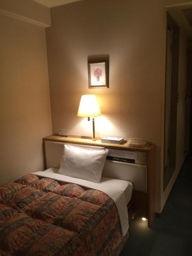 a hotel room with a bed with a lamp on it at ホテルパレスイン豊田 in Toyota