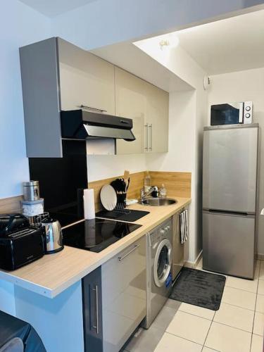 La cuisine est équipée d'une cuisinière, d'un évier et d'un lave-vaisselle. dans l'établissement ALEJÒ-HOME, Séjour apaisant!, à La Croix-de-Berny