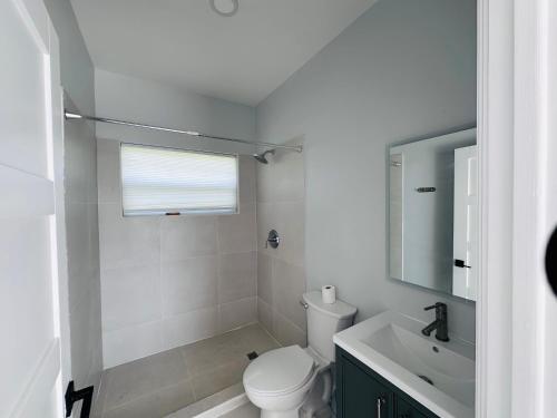 a white bathroom with a toilet and a sink at The Luxury Escape in Rouarné