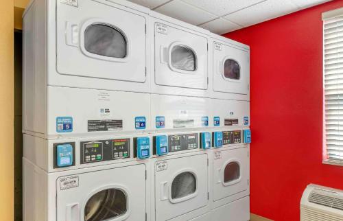 four washing machines in a room with a red wall at Extended Stay America Suites - Fort Wayne - South in Fort Wayne