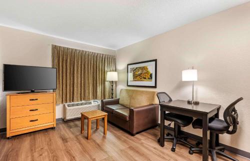 a hotel room with a desk and a couch and a television at Extended Stay America Suites - Cincinnati - Blue Ash - Reed Hartman in Blue Ash