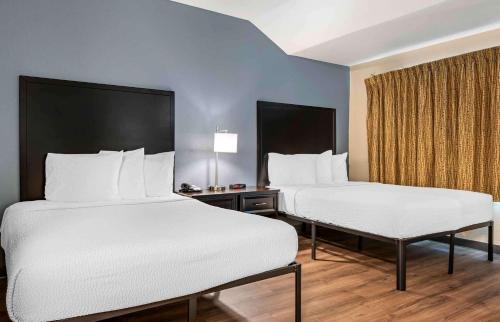 two beds in a hotel room with white sheets at Extended Stay America Suites - Cincinnati - Blue Ash - Reed Hartman in Blue Ash