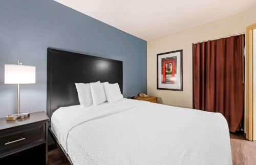 a large white bed in a hotel room with a lamp at Extended Stay America Suites - Cincinnati - Blue Ash - Reed Hartman in Blue Ash