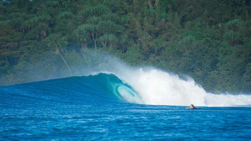 a person riding a large wave in the ocean at Diamond Island Eco Resort in Pulau Palambakbesar