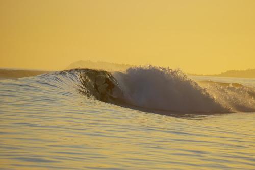 a surfer is riding a wave in the ocean at Diamond Island Eco Resort in Pulau Palambakbesar