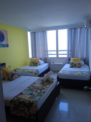 a hotel room with two beds and a window at Apartamento Playero in Cartagena de Indias