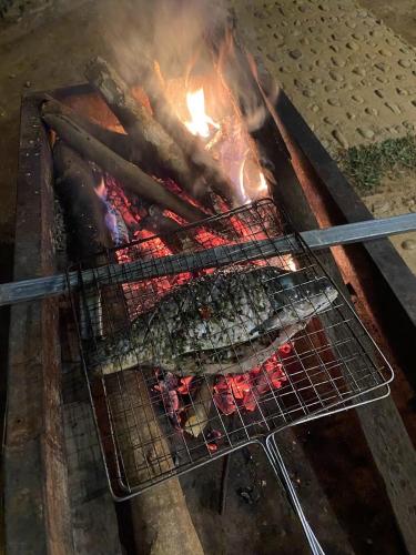 a grill with meat on top of a fire at Truong Nhan Tram Tau Homestay in Cham Ta Lao