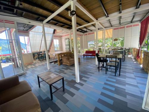 a living room with tables and chairs and windows at Gran Colibrí Adventure Park in San Pedro La Laguna