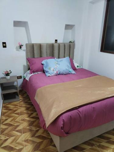 a bedroom with a large bed with purple sheets and pillows at Cori Wasi in Cusco