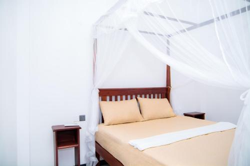 a bedroom with a bed with a mosquito net at River Relax Villa in Ahangama