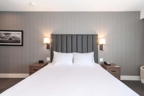 サスカトゥーンにあるSandman Signature Saskatoon South Hotelの白いシーツと枕が付いた大きなベッドのある寝室