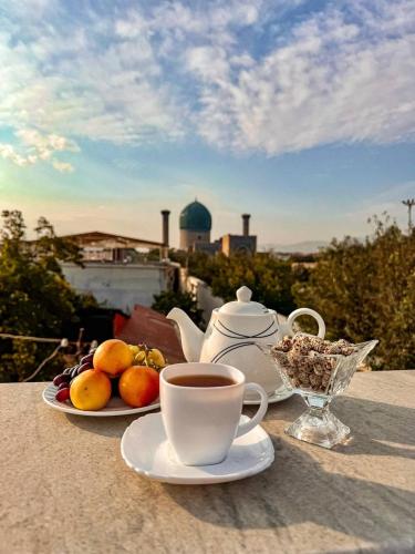 Гостевой дом Сардор في سمرقند: فنجان قهوة وصحن فاكهة على طاولة