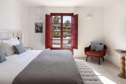 a bedroom with a large bed and a red chair at Vedema, a Luxury Collection Resort, Santorini in Megalokhori