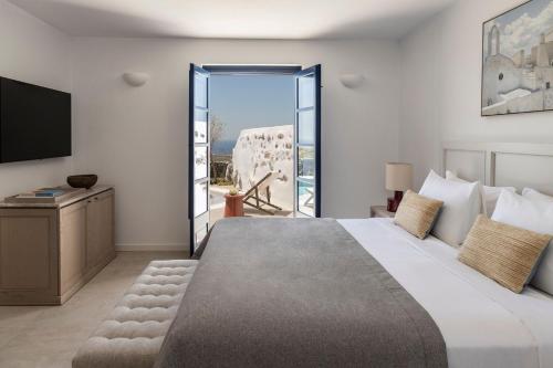 a hotel room with a large bed and a balcony at Vedema, a Luxury Collection Resort, Santorini in Megalokhori