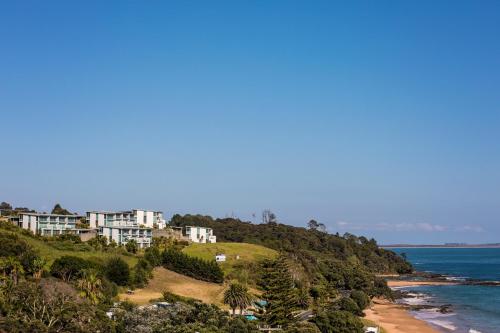 a house on a hill next to the ocean at Doubtless Bay Villas in Cable Bay