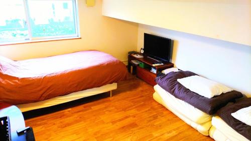 a hotel room with two beds and a flat screen tv at B&BHOUSE FAM - Vacation STAY 39533v in Ichinomiya