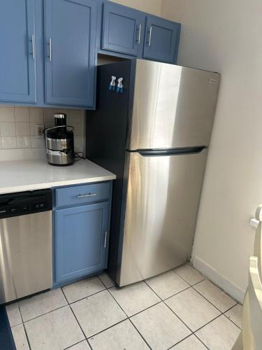 a kitchen with blue cabinets and a stainless steel refrigerator at Genevieves lovely suite in Jersey City