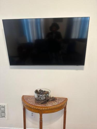 a tv on a wall with a bowl on a table at Genevieves lovely suite in Jersey City