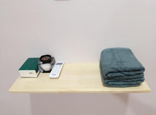 a wooden shelf with a towel and a remote control at ZamNur Bidara Chalet dan Homestay in Masjid Tanah