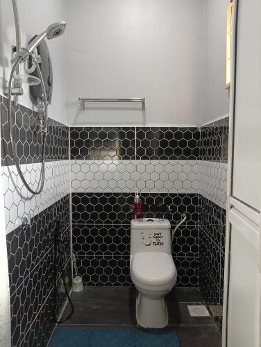 a bathroom with a toilet and black and white tiles at ZamNur Bidara Chalet dan Homestay in Masjid Tanah