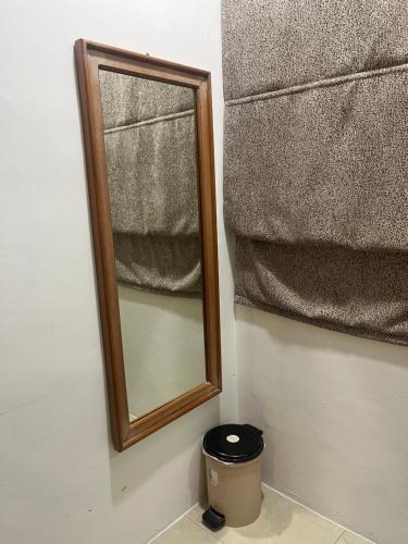 a mirror on a wall with a trash can next to it at Jo's in Miri