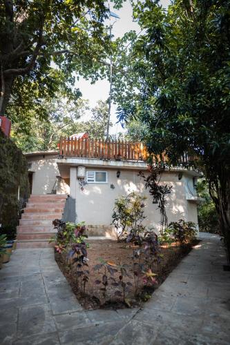 a white house with a deck on top of it at Jungle Ghar in Pachmarhī