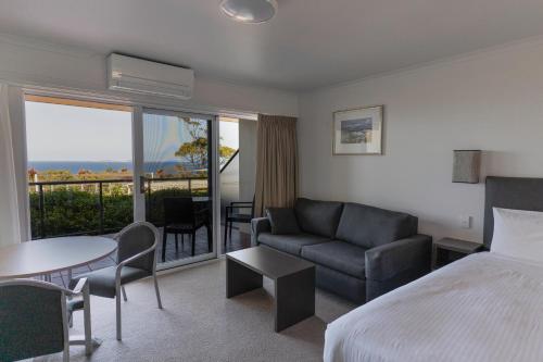 a hotel room with a bed and a couch and a table at Amooran Oceanside Apartments and Motel in Narooma