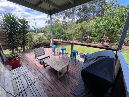 a deck with a bench and stools and a tent at Dacelo in Halls Gap