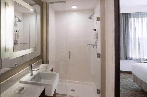 a white bathroom with a shower and a sink at SpringHill Suites by Marriott Orlando at FLAMINGO CROSSINGS Town Center-Western Entrance in Orlando