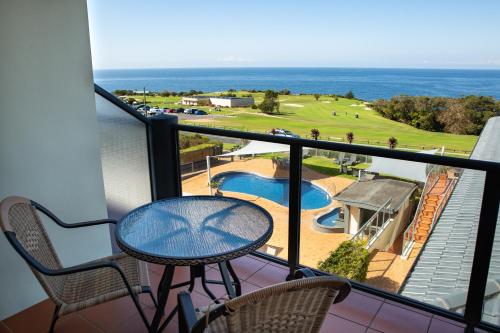 a balcony with a table and chairs and the ocean at Amooran Oceanside Apartments and Motel in Narooma