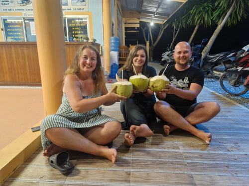 three people sitting on the floor holding coconuts at Peace Lanta Mansion in Ko Lanta