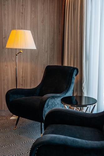 a living room with two chairs and a table and a lamp at Sky Airport Hotel in Cluj-Napoca