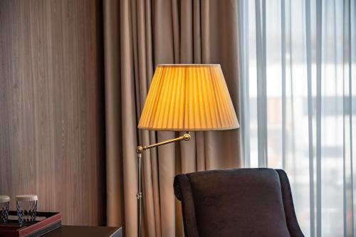 a lamp sitting next to a chair next to a window at Sky Airport Hotel in Cluj-Napoca