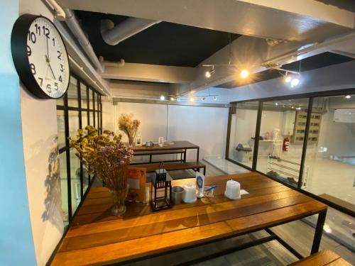 a room with a wooden table and a clock on the wall at Sleep At Home - Don Mueang in Bangkok