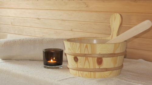 a candle and a wooden bucket with a wooden spoon at Böhmerwald Pur2 mit Sauna in Klaffer am Hochficht