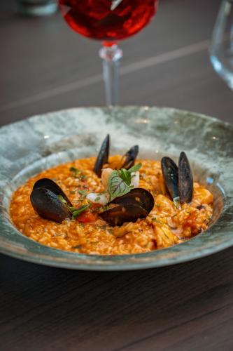 a plate of food with mussels and a wine glass at Sky Airport Hotel in Cluj-Napoca