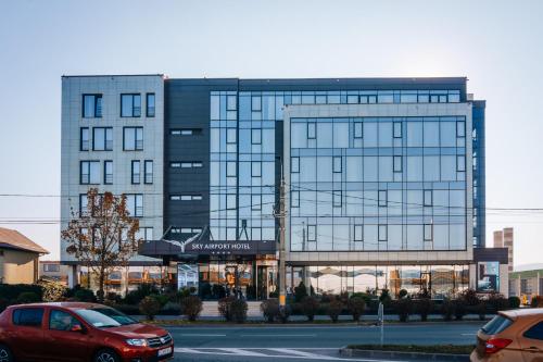 a large glass building with cars parked in front of it at Sky Airport Hotel in Cluj-Napoca