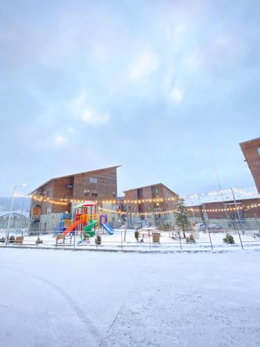 un parque infantil frente a un edificio en la nieve en Villa Monte Bakuriani 10, en Bakuriani