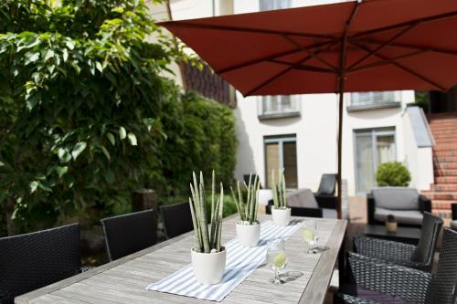 a wooden table with plants and an umbrella at Hotel Kleines Meer in Waren