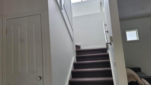 a stairway with brown stairs and a white door at Bliss Stay Cosy Home 3Bedroom 2Bath in Croydon