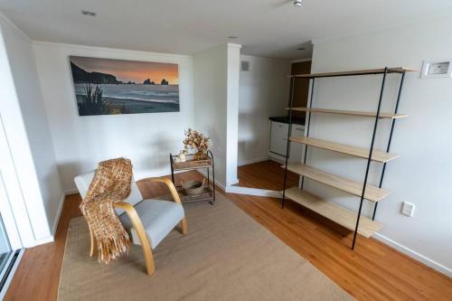 a living room with a chair and a book shelf at Hilltop Escape - Spa & Views in Greymouth
