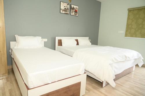two beds in a room with white sheets at shangrila stay in Bodh Gaya