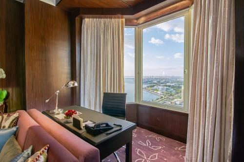 a room with a pink couch and a large window at Diamond Hotel Philippines in Manila