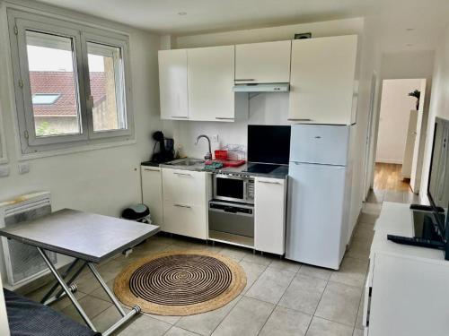 a kitchen with white appliances and a table in it at Le canoe in Vaires-sur-Marne