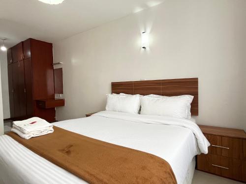 ナクルにあるMilimani Executive Suites With Pool, GYM, Secure Parkingの白いシーツが敷かれた大きなベッドのある寝室